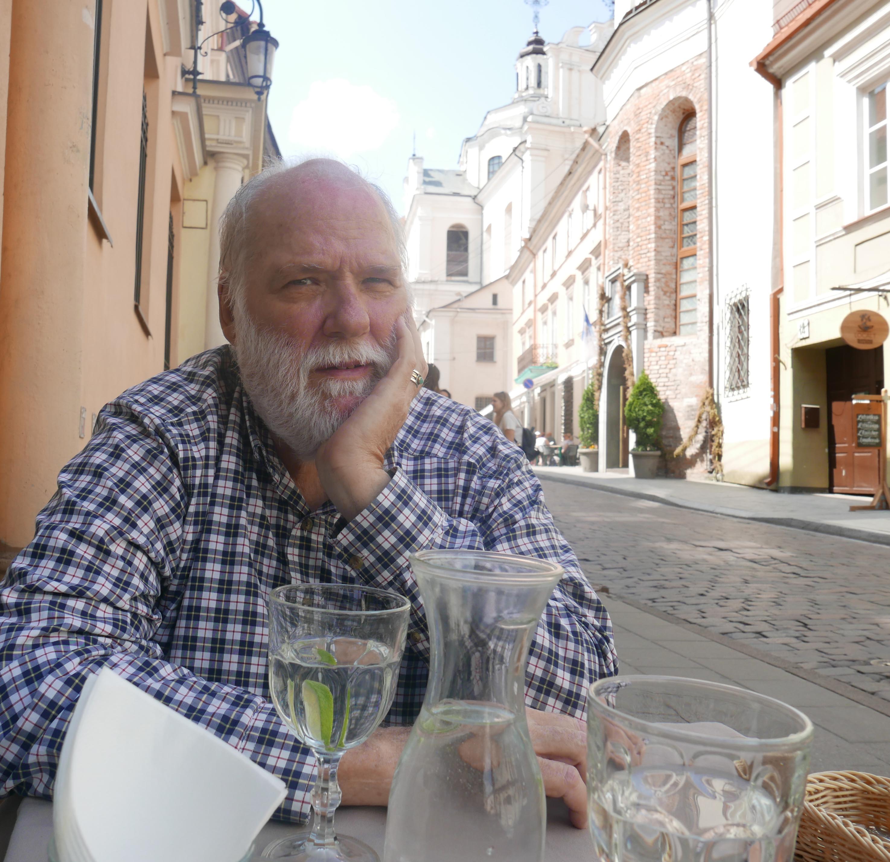 briggs sitting at table with lithuanian archtecture behind him