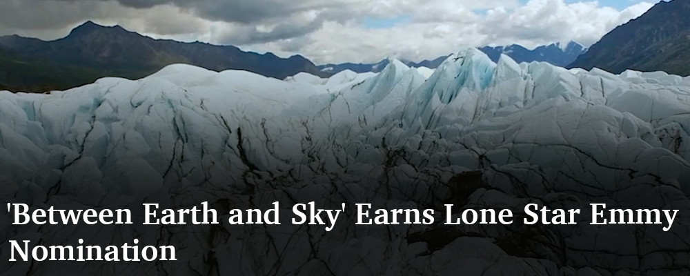clouds and mountains in background, ice with veins of dirt in the foreground