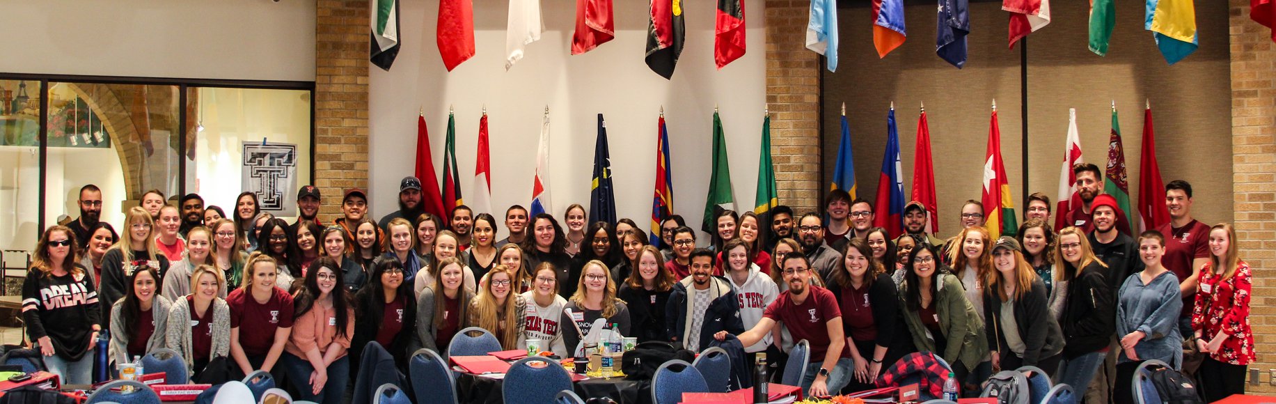 Tutors posing in front of cultural flags at the tutor training day