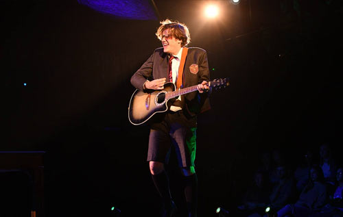 Student with guitar playing on stage