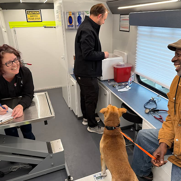 CARES Mobile Unit Veterinary faculty and student inside the CARES veterinary mobile unit helping a person and their dog