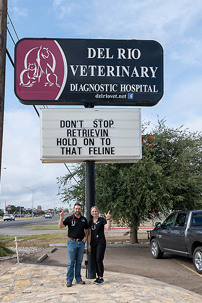 Makenna taking a picture with a veterinarian by clinic sign