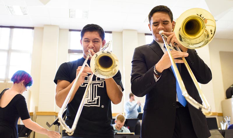 2 students playing their trombones