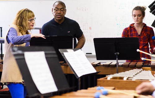 Faculty & students in a band hall playing instruments