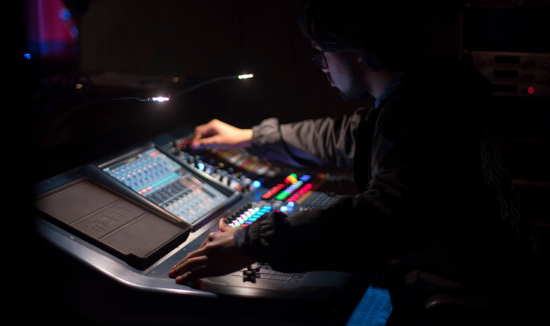 TTU theatre student with headphones behind a sound board