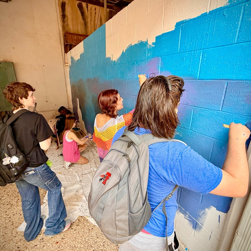 Art students painting the base coat for wall mural