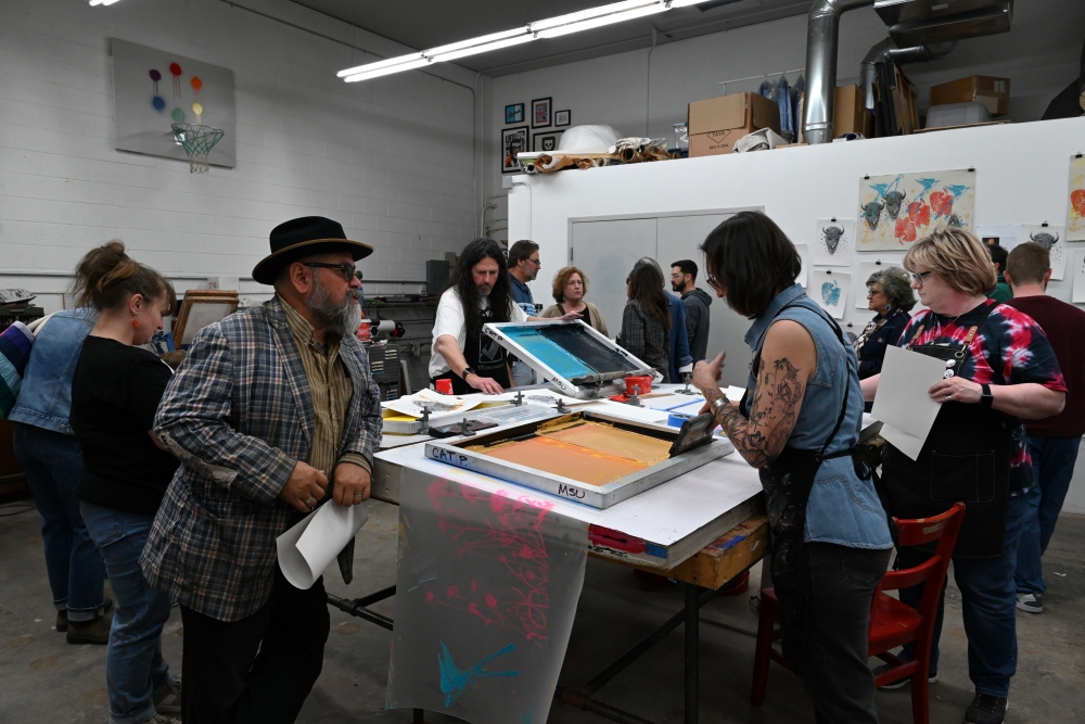 Alums Catherine Prose and John Hitchcock pulling prints for people at the First Friday Art Trail.